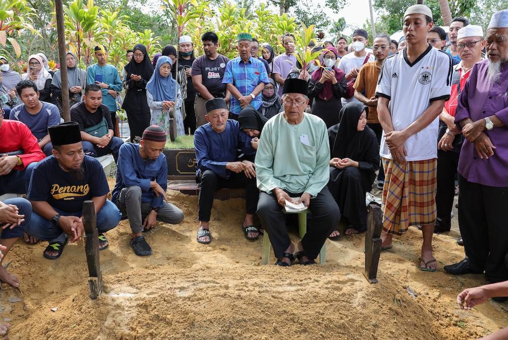 Kamalul Arifin Ahmad (duduk depan tiga, kiri) , 66, bersama ahli keluarga terdekat mendengar bacaan talkin di pusara anaknya, Nurul Nazihah Kamalul Arifin yang maut dalam kemalangan. - Foto Bernama