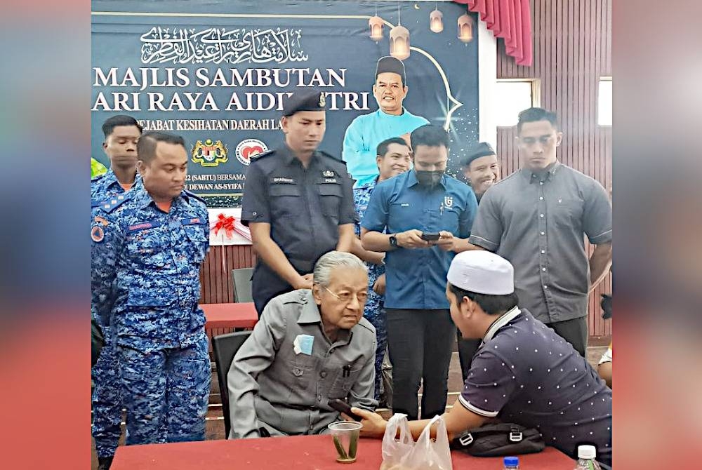 Dr Mahathir bertanya khabar seorang mangsa banjir di PPS Dewan Syifa ketika lawatannya pada Isnin.