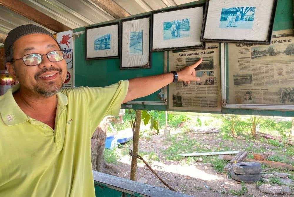 Mohd Rosdi menunjukkan keratan akhbar tentang pembinaan Jambatan Palekbang yang ditampal di dinding kedai kopinya.