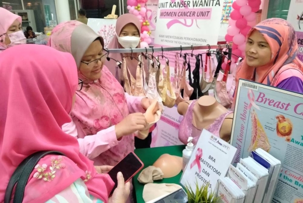 Bakiah (kiri) dan Hasmah menunjukkan cara penggunaan bra mastektomi dan prostesis semasa Program Pink October-High Tea sempena Bulan Kesedaran Kanser Payudara Sedunia di Sungai Petani pada Sabtu.