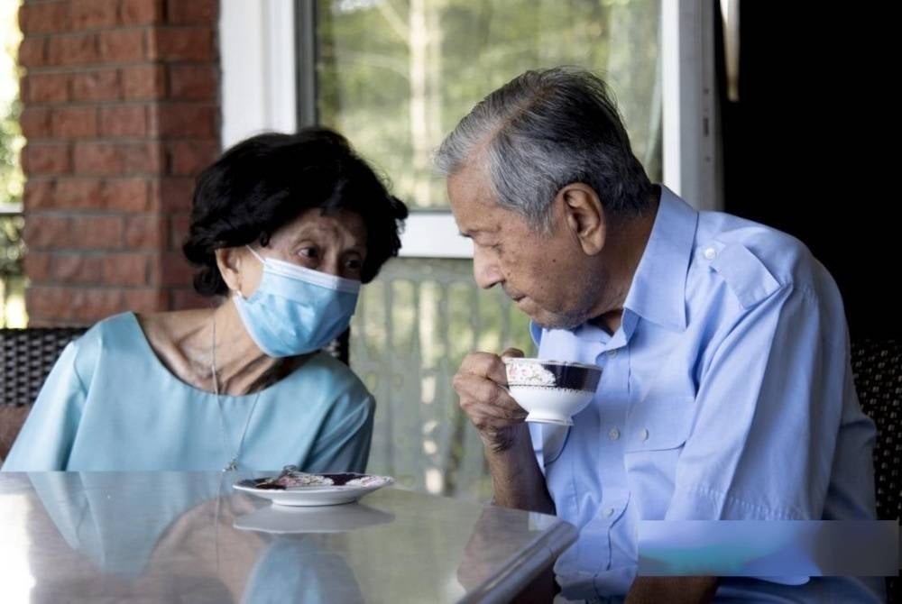 SETIA MENEMANI... Gambar dirakam pada awal Februari lalu sewaktu Dr Siti Hasmah (kiri) berbual dengan Dr Mahathir di kediaman mereka.