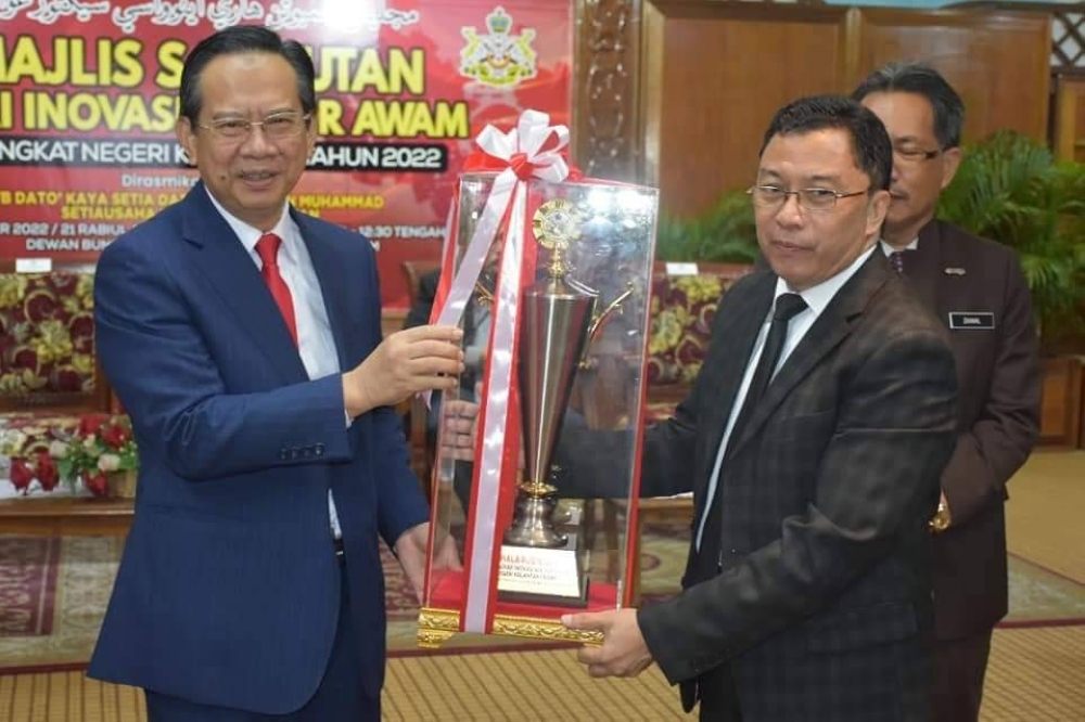 Nazran (kiri) menyampaikan anugerah kepada pemenang semasa Majlis Sambutan Hari Inovasi Sektor Awam Negeri Kelantan Tahun 2022 di Dewan Teratai, Kompleks Kota Darulnaim, Kota Bharu pada Selasa.