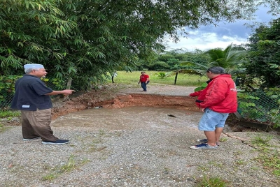 Zubir (kiri) meninjau jalan di Kampung Tanjung, mukim Ulu Melaka,Langkawi yang terputus akibat banjir.
