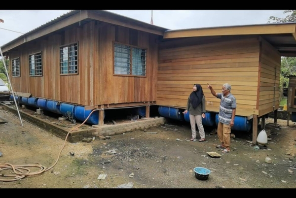 A Bakar (kanan) menunjukkan rumah terapung yang dibina sebagai persiapan menghadapi banjir.