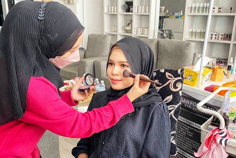 Nur Aliya Saffiya sedang mengenakan solekan pada wajah pelanggan.