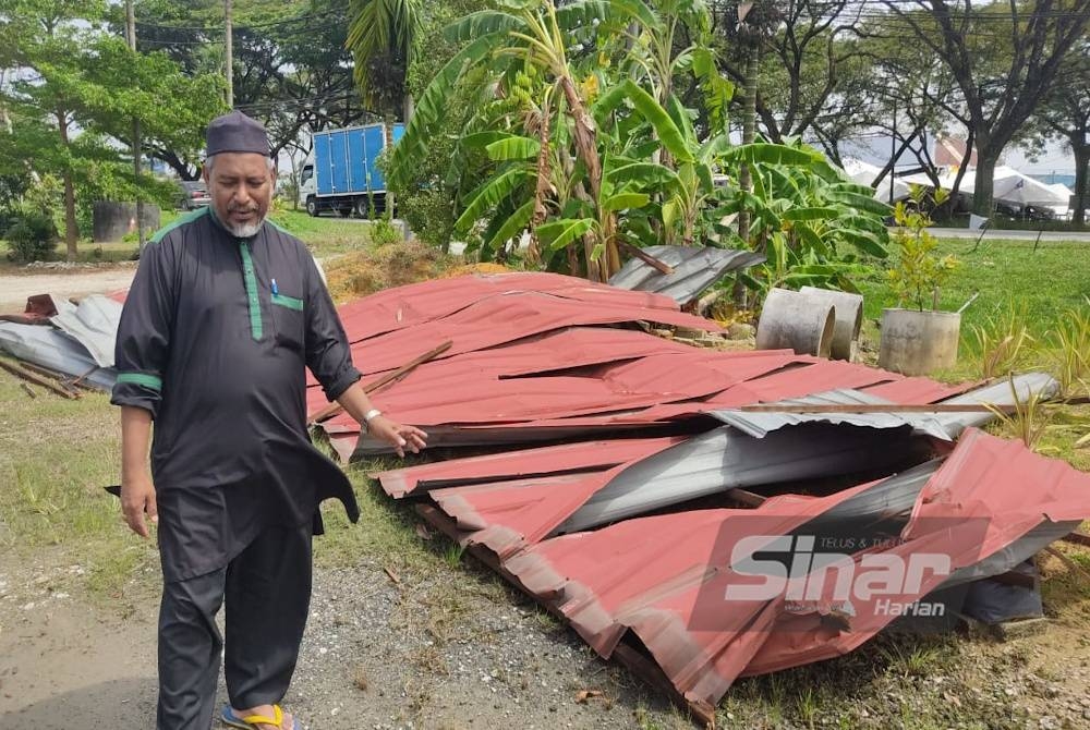 Mohamad Zaini menunjukkan bumbung rumahnya yang diterbangkan ribut pada petang Rabu.