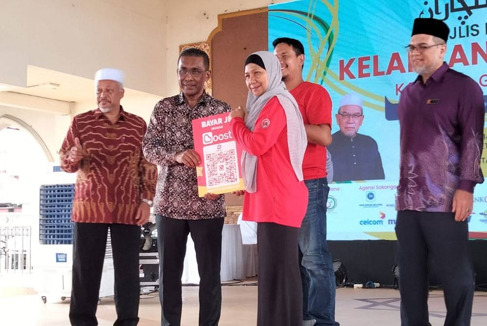 Takiyuddin (dua dari kiri) menyampaikan plakad pembayaran melalui digital kepada peniaga pada Majlis Pelancaran Karnival Go Digital pada Khamis.