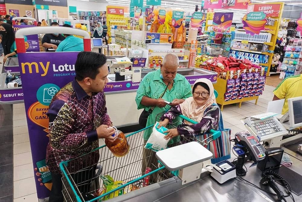 Wan Saiful (kiri) menyampaikan sumbangan kepada penerima MyKasih Foundation di Lotus di sini pada Khamis.