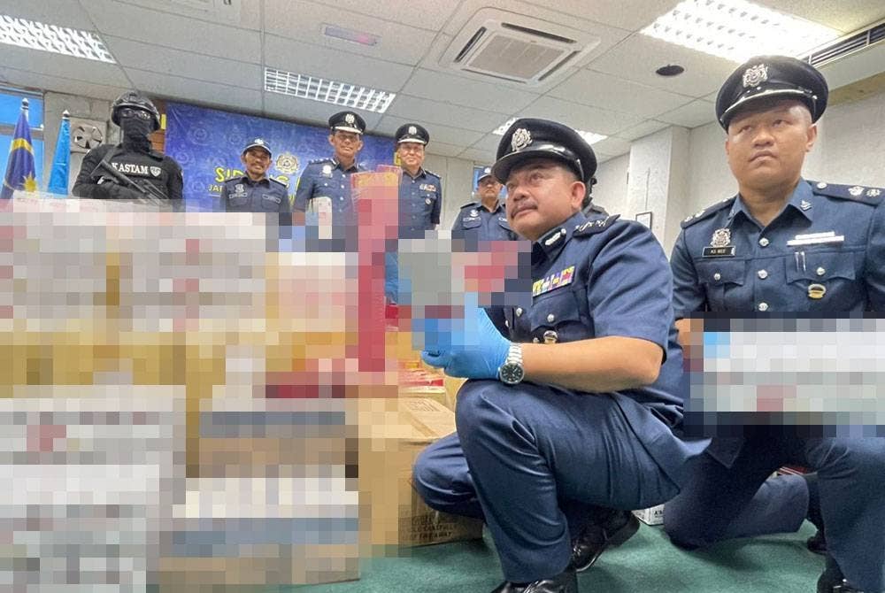 Hamisan (duduk, dua dari kanan) menunjukkan barangan seludup yang dirampas pada 4 Oktober lalu.