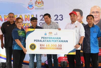 Ronald (tiga dari kiri) menyaksikan Pemangku Timbalan Pengurus Besar (Pembangunan) KADA, Mohd Razif Abdullah (dua dari kanan) menyampaikan sumbangan peralatan pertanian kepada wakil petani, Norisah Pisik pada program Semarak Tani Keluarga Malaysia di Telupid. - Foto Bernama