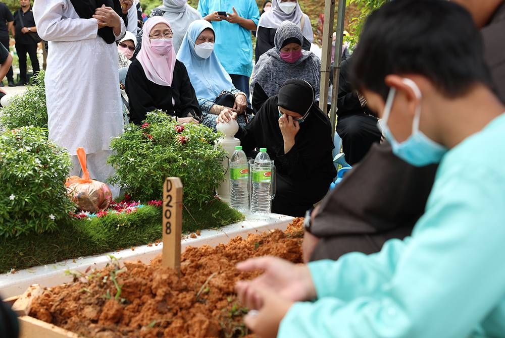 Dr Wan Azizah (duduk, kiri) di pusara ibunya, Datin Mariah Khamis sebaik dikebumikan di Tanah Perkuburan Islam Ukay Perdana pada Isnin - Foto Bernama
