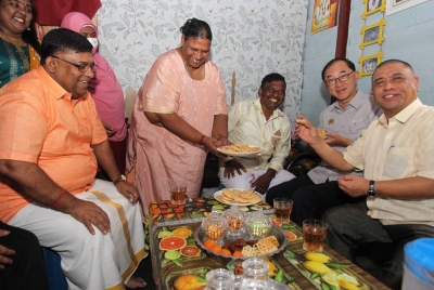 Saarani (kanan) menikamti hidangan muruku yang disediakan Devagi (tiga dari kiri) ketika singgah menyambut Deepavali di Kampung Chengai, Sungkai pada Isnin.