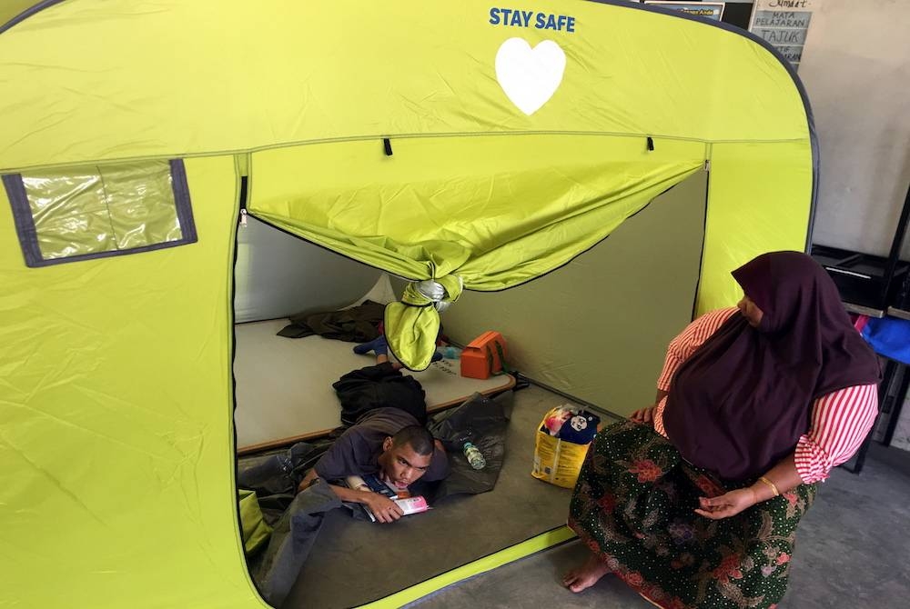 Zaiton Suman, 55, (kanan) bersama anak istimewanya, Muhammad Iman Farhan Abdullah, 17, ditempatkan di PPS Sekolah Kebangsaan Durian Tunggal selepas rumah mereka di Kampung Bukit Tambun dinaiki air. - Foto Bernama