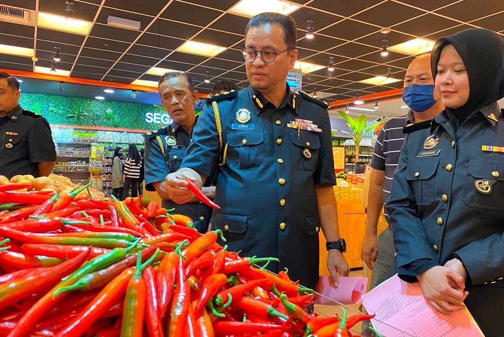 Azman memeriksa cili merah semasa mengadakan pemantauan pematuhan skim harga maksimum musim perayaan Deepavali di sebuah pasar raya di Kota Bharu pada Selasa.
