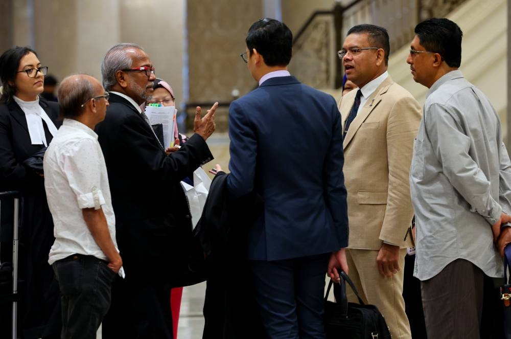 Lokman (dua dari kanan) berbincang bersama peguamnya Mohamed Shafee (tiga dari kiri) di Kompleks Istana Kehakiman pada Rabu. - Foto Bernama
