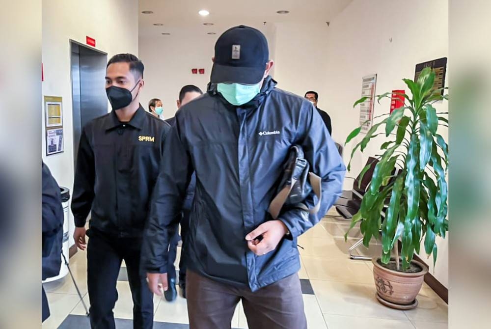 Tertuduh (kanan) hadir di Mahkamah Sesyen Shah Alam dengan bagi menghadapi dua pertuduhan kes rasuah pada Khamis.