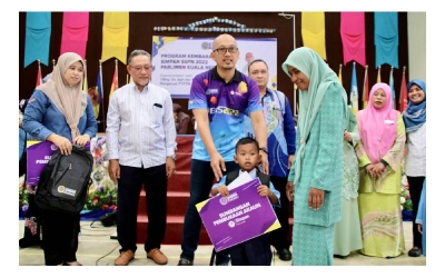 Dr. Apli menyampaikan replika kad Simpan SSPN Prime kepada murid Kemas sebagai penerima Program Kembara Keluarga Simpan SSPN Kawasan Kuala Nerus. 