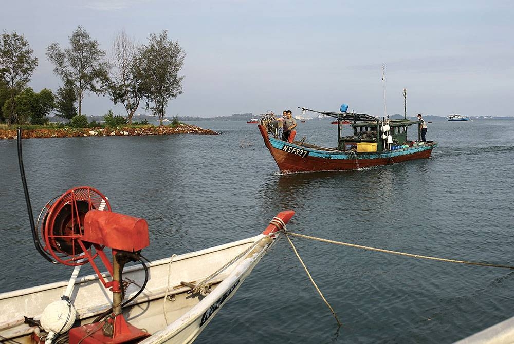 Sebuah bot nelayan pantai pulang ke jeti dengan membawa hasil laut di perairan pantai Port Dickson. 