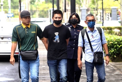 Tertuduh (dua dari kiri) diiringi polis di Mahkamah Majistret Seremban pada Jumaat.