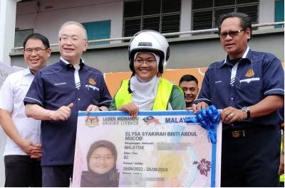 Ka Siong (dua dari kiri) menyerahkan lesen B2 kepada penerima Program BLKM di SMK Suria Perdana pada Sabtu.