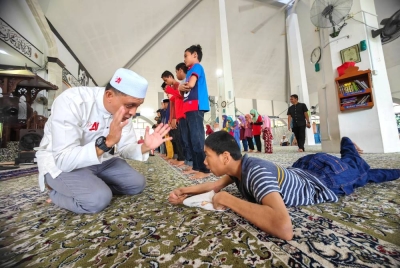 Ahmad Idham menunjukkan cara solat kepada Luqman Hakim yang menghidap cerebral palsy.