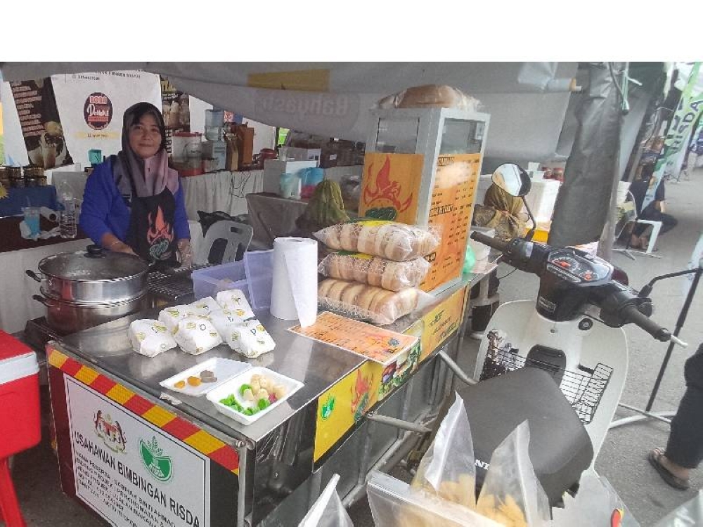 Sabihah di hadapan gerai burger yang disumbangkan oleh RISDA.