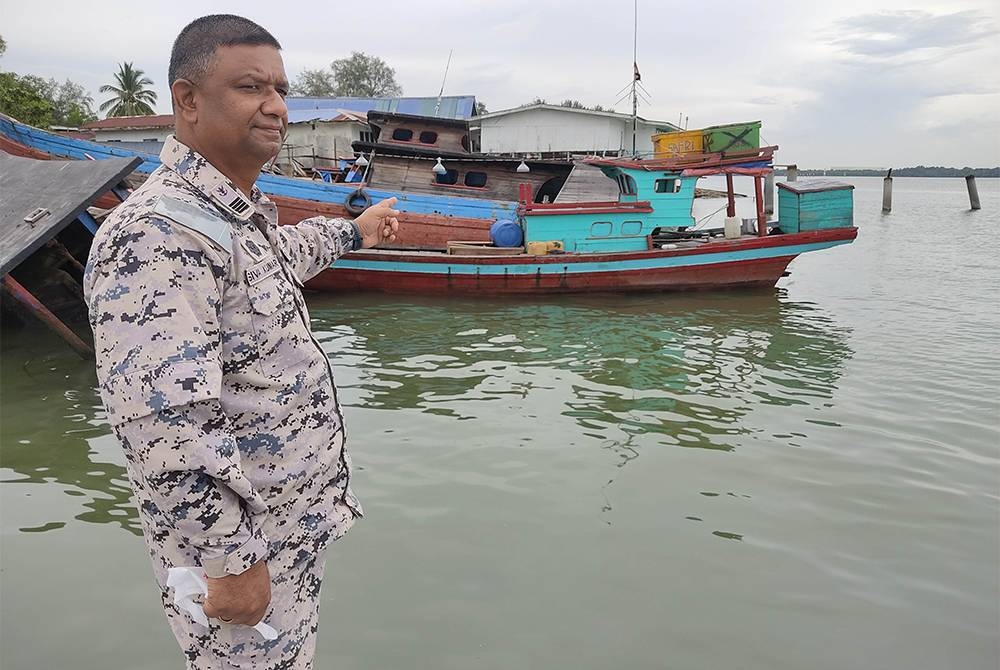 Siva Kumar menunjukkan bot kayu yang digunakan sindiket bagi membawa 44 PATI dari Indonesia sebelum ditahan di Tanjung Layang, Selangor pada Isnin.