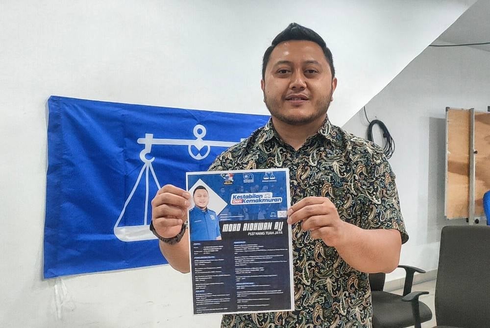 Mohd Ridhwan menunjukkan poster biodata beliau di Pejabat BN Parlimen Hang Tuah Jaya di Bukit Katil, Melaka pada Rabu.