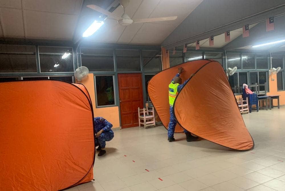 Anggota APM melakukan kerja-kerja pemasangan kubikal di salah sebuah PPS yang di buka ekoran banjir kilat melanda tiga kampung di Raub pada Khamis. - Foto APM