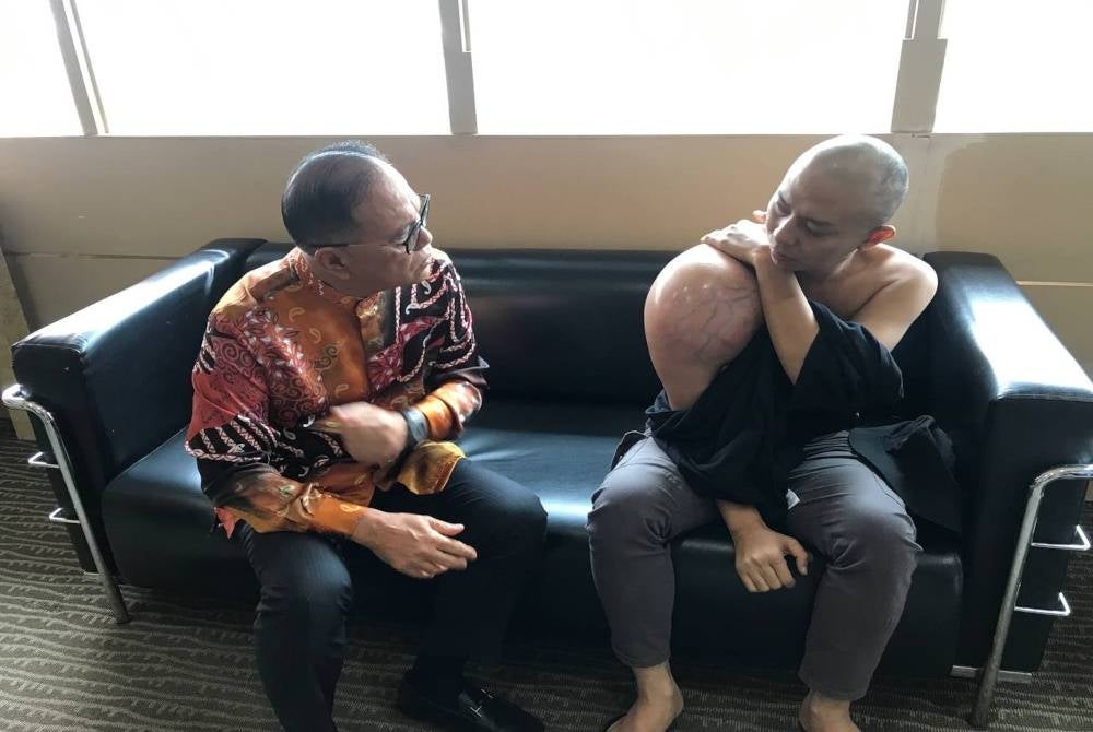 Wan Rosdy (kiri) mendengar kisah penderitaan Muhammad Adli selepas disahkan menghidap kanser tulang sejak 12 September lalu.