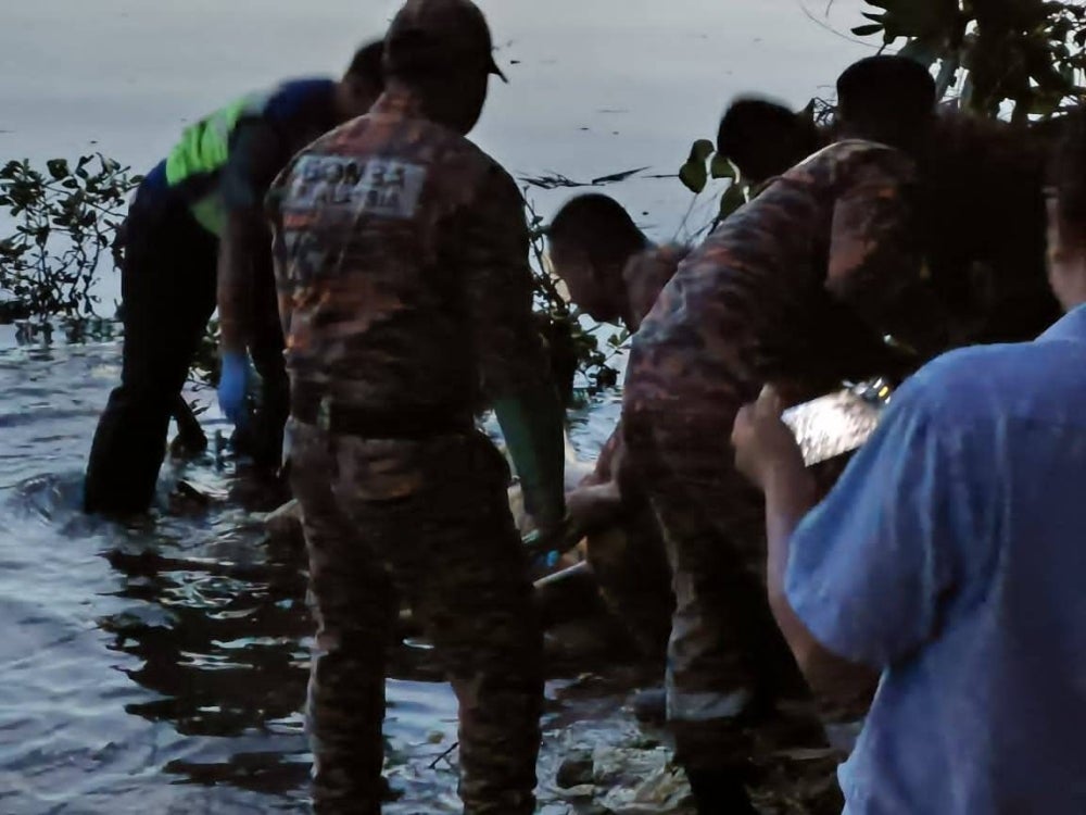 Anggota bomba mengangkat mayat yang ditemukan terapung di sungai di bawah Jambatan Bakar Batu, Johor Bahru pada Khamis.