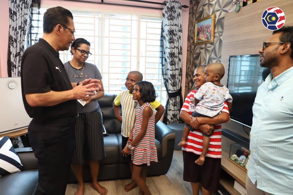 Ab Ghani bertanya sesuatu kepada anak-anak mendiang P Rajes semasa menziarahi keluarga tersebut pada Khamis. - Foto MFL