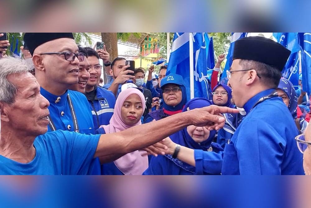 Asyraf Wajdi (kanan) bersalam dengan penyokong selepas keluar dari Pusat Penamaan Calon di Dewan Serbaguna Gerik.