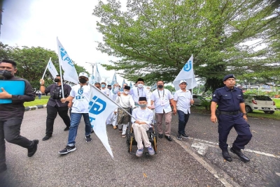 Ahmad Idham menolak kerusi roda anaknya Ahmad Firdaus sambil ditemani isteri serta tiga lagi anaknya ke Pusat Penamaan Calon di Kompleks Pentadbiran Port Dickson.