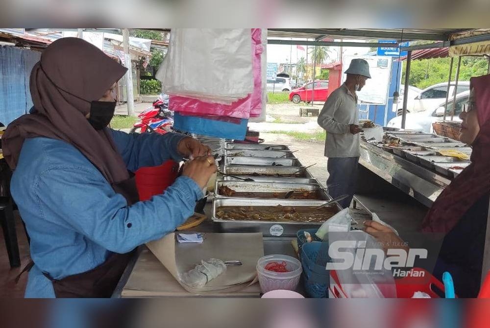 Mastura (kiri) melayani pelanggan di kedai makannya berdekatan Hospital Sultanah Bahiyah, Alor Setar pada Sabtu.