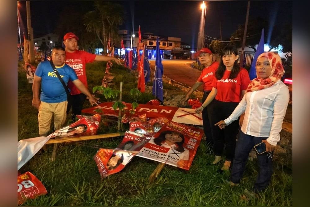 Yu Man (dua dari kanan) menunjukkan bahan kempen PH yang didakwa dirosakkan individu tidak dikenali.