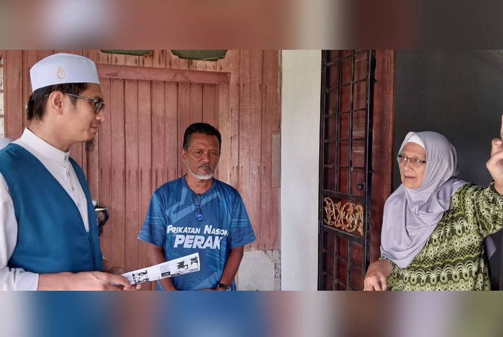 Muhammad Rif'aat (kiri) ketika mengadakan kempen dari rumah ke rumah di Kampung Raban pada Selasa.