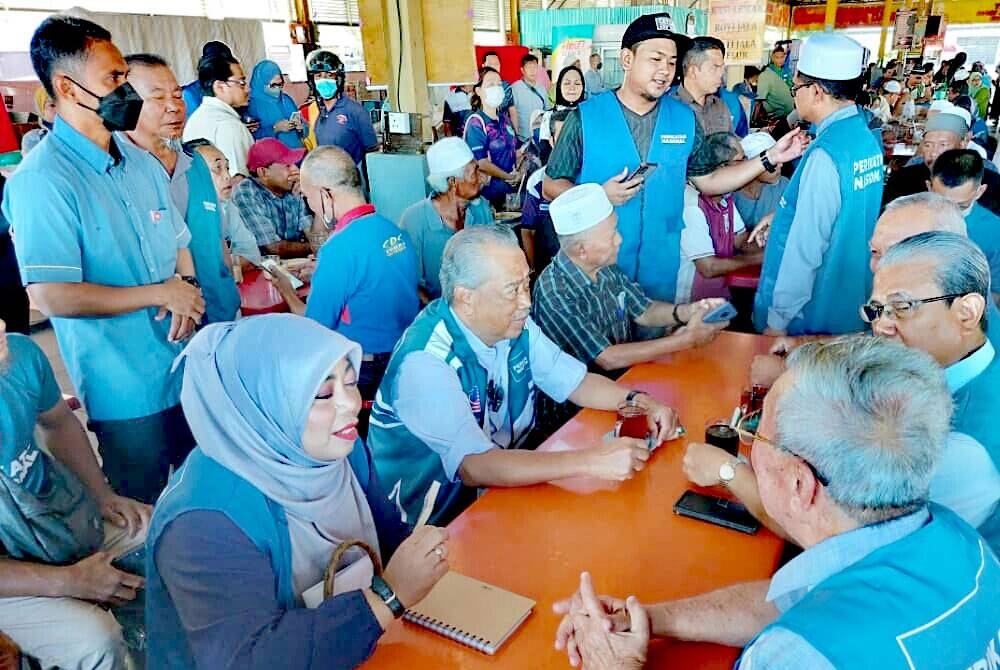 Muhyiddin (tengah dari kiri) beramah mesra bersama masyarakat Jitra di Medan Selera Pekan Jitra Dua, pada Selasa.
