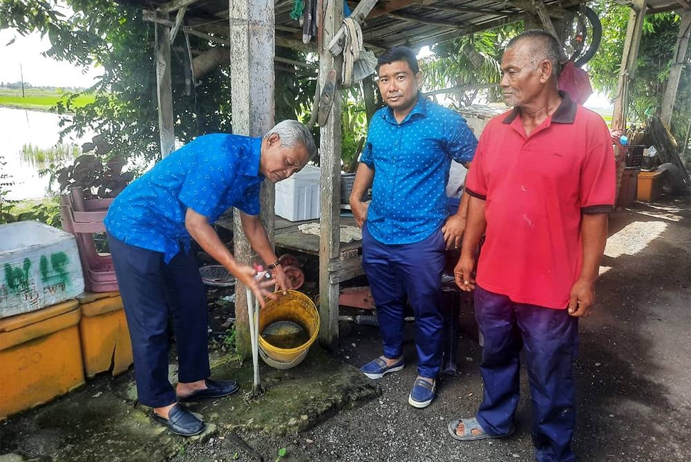 Othman (kiri) ketika meninjau masalah bekalan air di Kampung Pulai, pada Selasa.