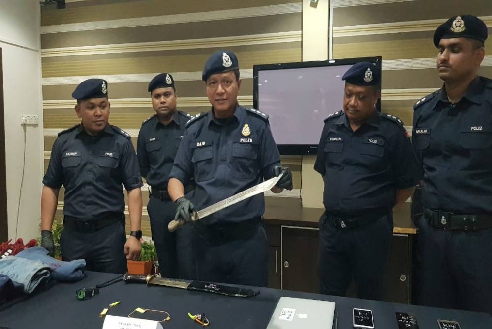 Mohd Zaid (tengah) menunjukkan senjata parang yang dipercayai digunakan suspek ketika melakukan samun sebuah klinik pergigian di daerah Kajang baru-baru ini.