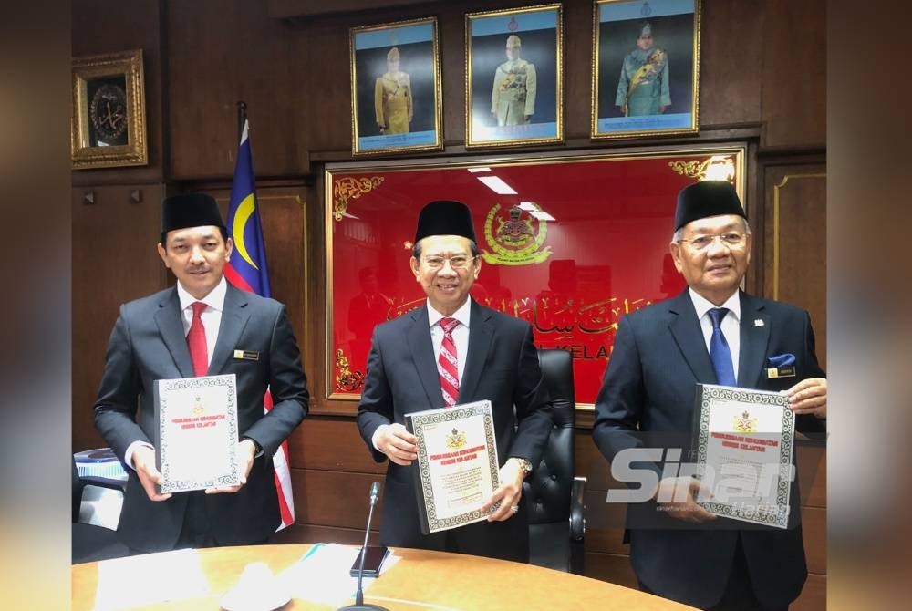 Nazran (tengah) bersama Mamat Ariffin (kanan) dan Nik Mohd Shafriman (kiri) menunjukkan buku senarai penerima Pengurniaan Kehormatan Negeri Kelantan pada 2022. - Foto Sinar Harian