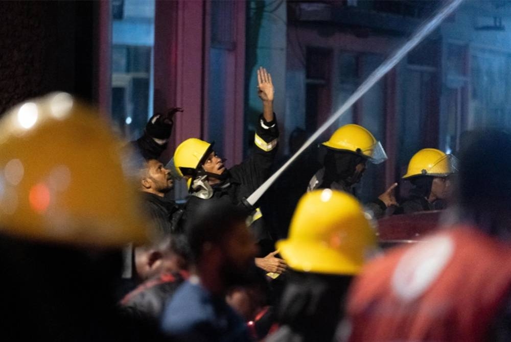Anggota bomba cuba memadamkan kebakaran di sebuah bangunan yang menempatkan pekerja asing di Maldives. - Foto Mohamed Shaabin/AFP