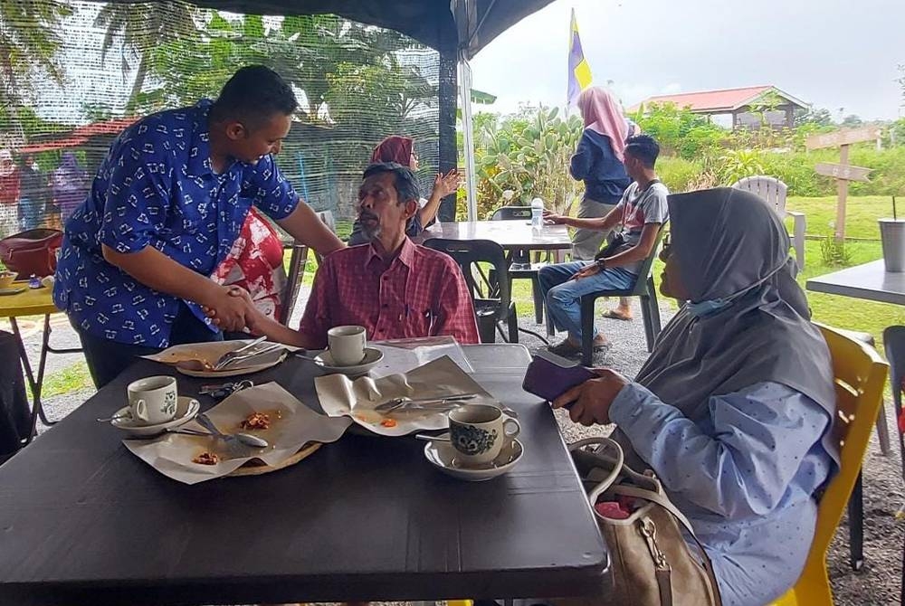 Syed Atif Syed Abu Bakar (kiri) menyantuni orang ramai semasa melakukan 'walkabout' dalam kawasan DUN Pauh pada Khamis.