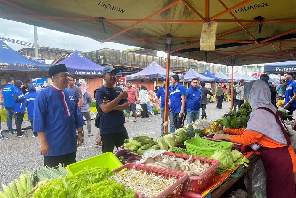 Ahmad Jazlan (kiri) beramah mesra bersama peniaga di Pasar Tani Machang pada Jumaat.