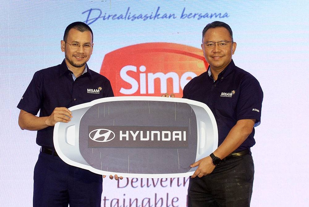 Ahmad Zulqarnain menerima replika kunci kereta Hyundai Kona Electric Lite dari Ketua Perniagaan Caterpillar, Sime Darby Industrial, Nor Azman Muzaid pada majlis Jalinan Rakan Korporat MSAM 2022 yang diadakan di Menara PNB, Kuala Lumpur.