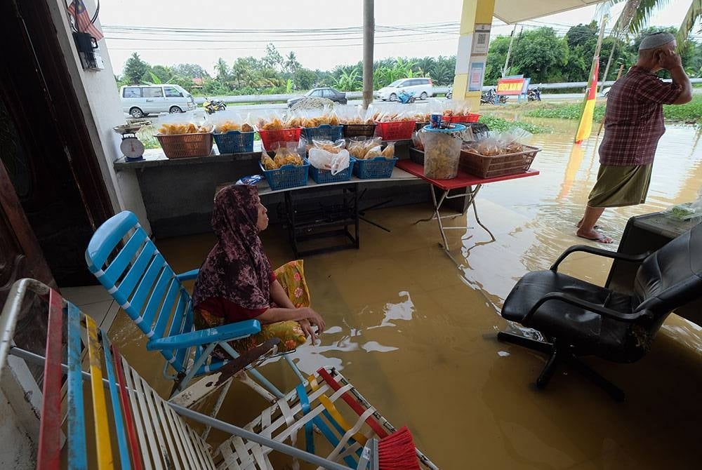 Penduduk kampung Hamzah Jamaluddin, 58, (kanan) tetap meneruskan perniagaan kerepeknya walaupun rumahnya telah dinaiki air ekoran banjir kilat yang berlaku ketika tinjauan fotoBernama di sekitar Klang hari ini.