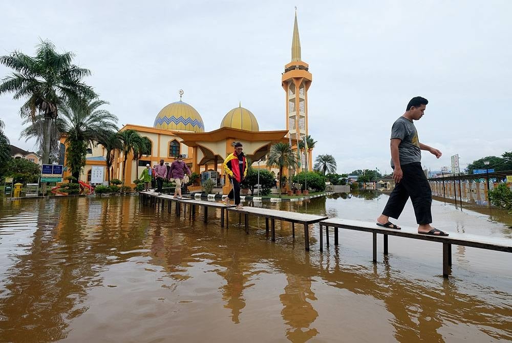 Jemaah masjid menggunakan titi yang dibuat khas ekoran pekarangan masjid dinaiki air selepas selesai menunaikan solat Asar di Masjid As-Syarif Jalan Hamzah Alang Meru Klang hari ini.