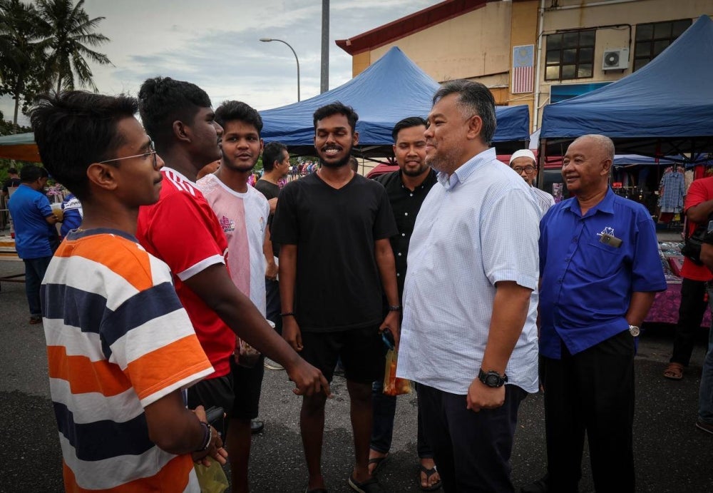 Rozabil (depan kanan) dan Nurulhisham (belakang kanan) mendengar permasalahan sekumpulan anak muda di pasar malam Simpang Empat, Arau pada Jumaat.