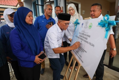 Wan Rosdy menandatangani plak perasmian pada Majlis Pelancaran Rumah Pahang di Felda Sungai Retang pada Jumaat. - Foto Bernama