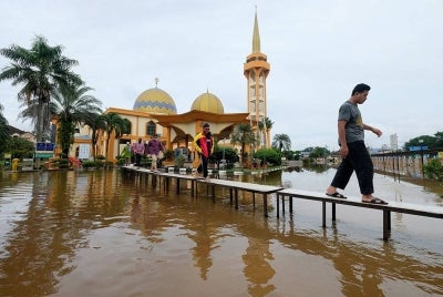 Jemaah masjid menggunakan titi yang dibuat khas ekoran pekarangan masjid dinaiki air selepas selesai menunaikan solat Asar di Masjid As-Syarif Jalan Hamzah Alang Meru Klang hari ini.